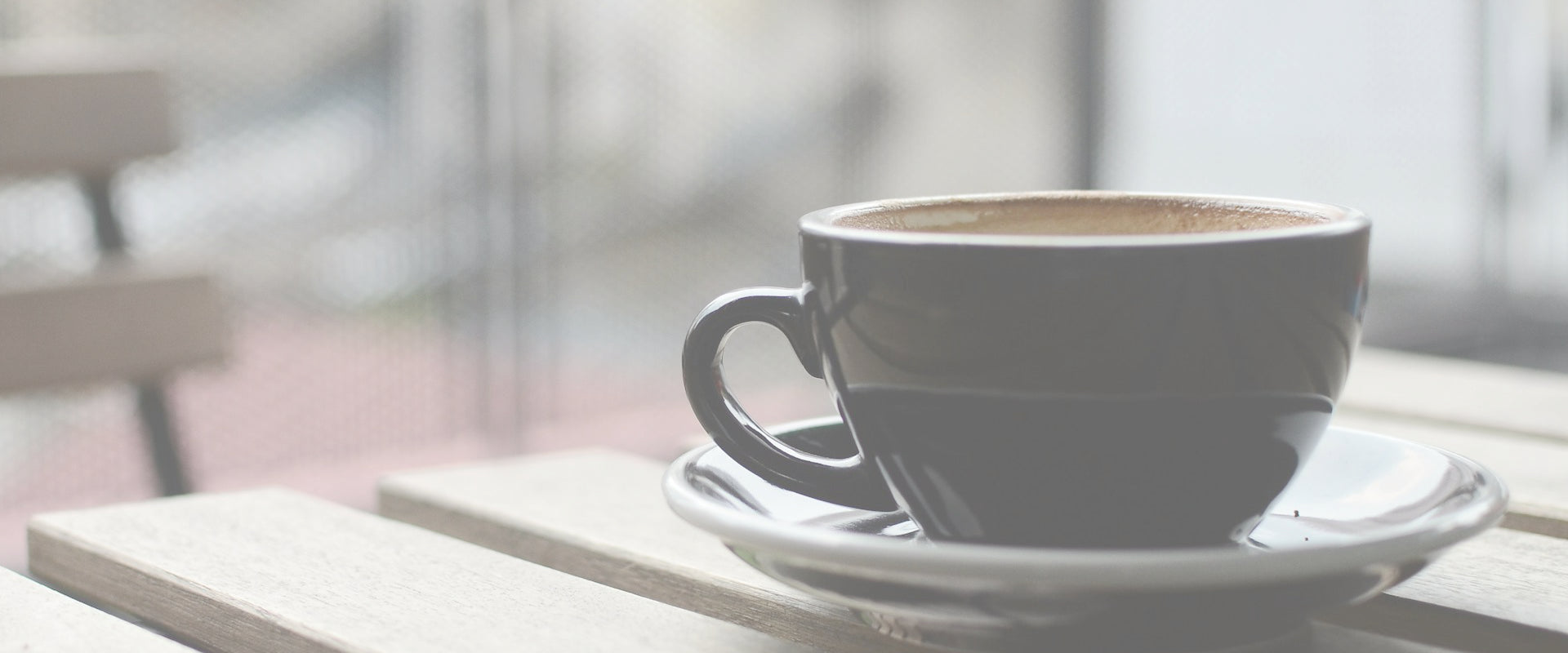 Coffee cup on a saucer with a blurred outdoor background