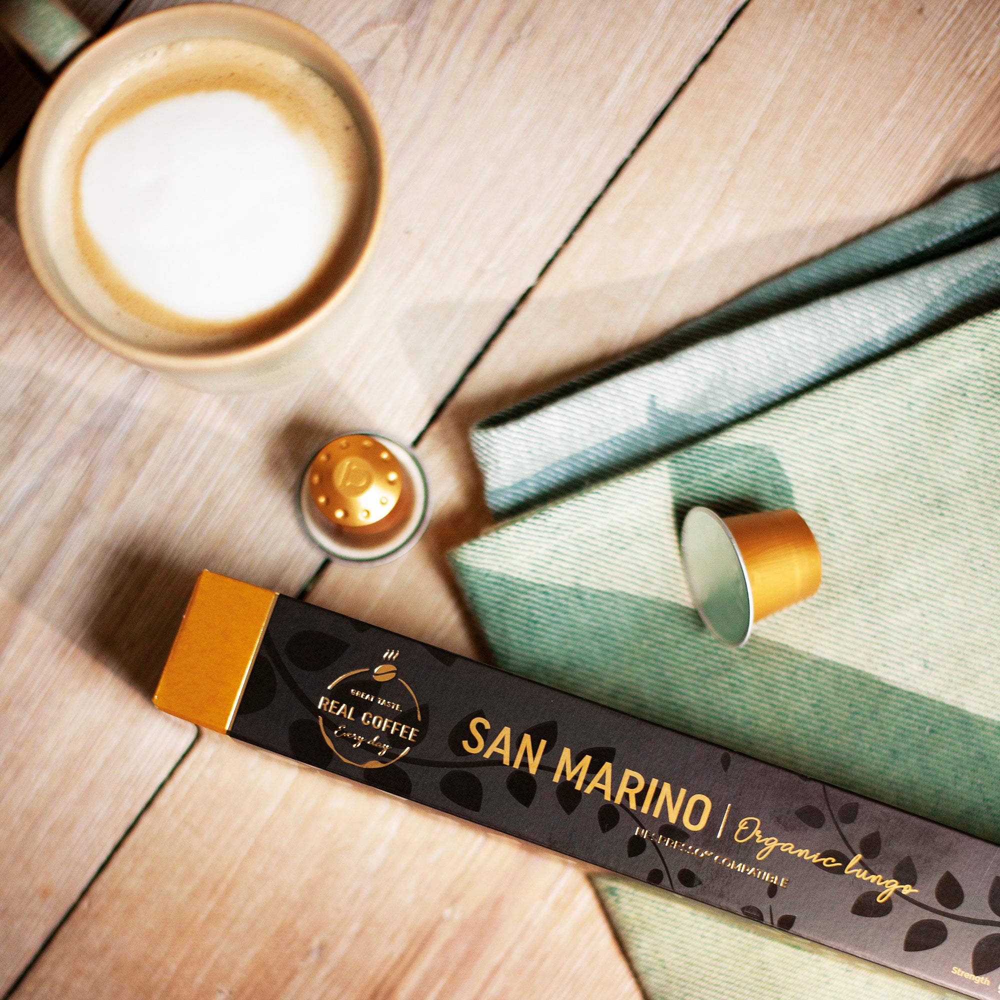 San Marino Nespresso® compatible coffee capsules packaging with a cup of coffee on a wooden surface
